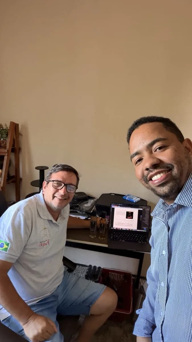 Victor Torres trabalhando com o produtor da Cachaça Kaipú no laptop, com garrafas do produto na mesa
